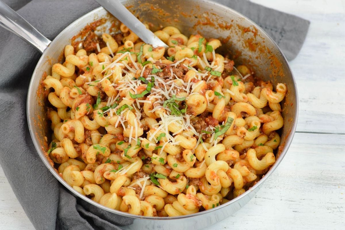 A Skillet of pasta with sauce, garnished with parsley.