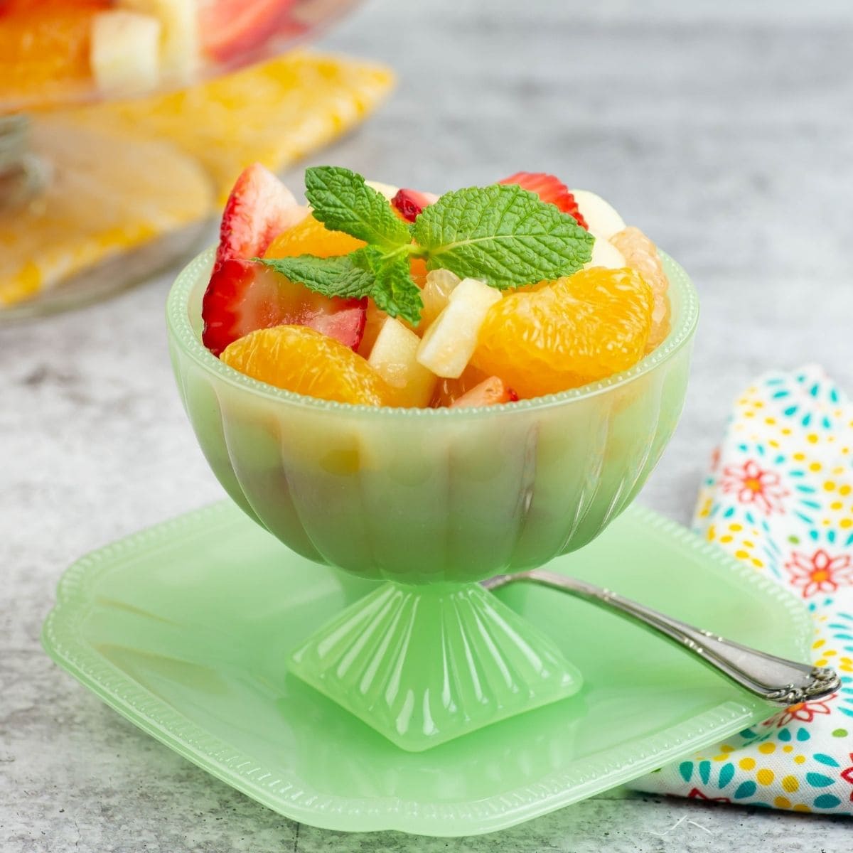 Individual serving bowl filled with citrus fruit salad garnished with a sprig of fresh mint.