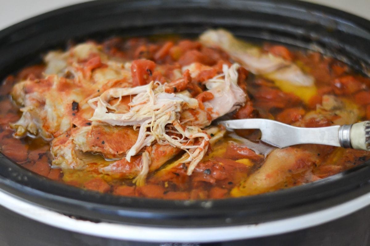 Slow cooker filled with a shredded pork shoulder made in the Cuban style with a homemade mojo marinade.