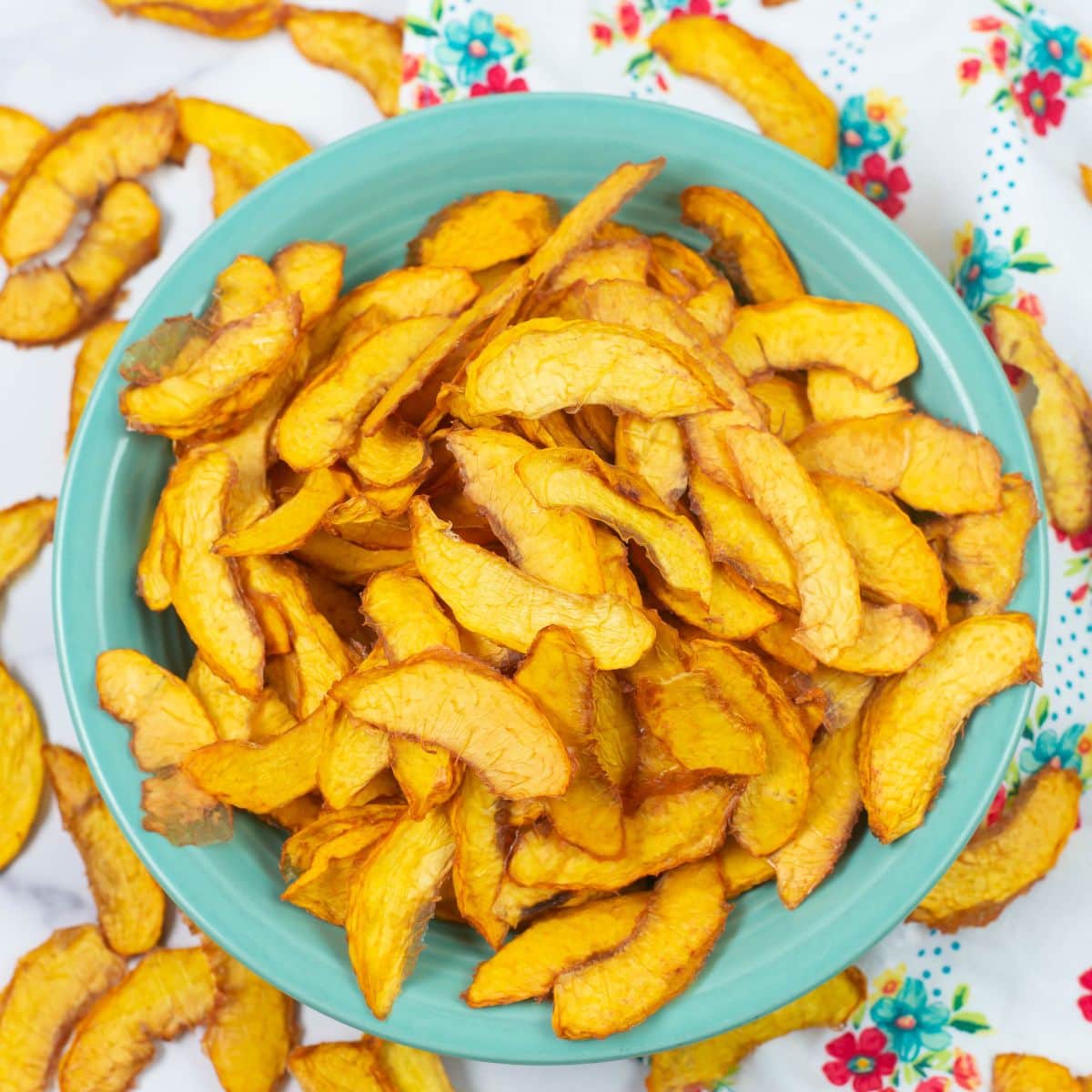 Sliced dehydrated peaches in a bowl on a napkin.