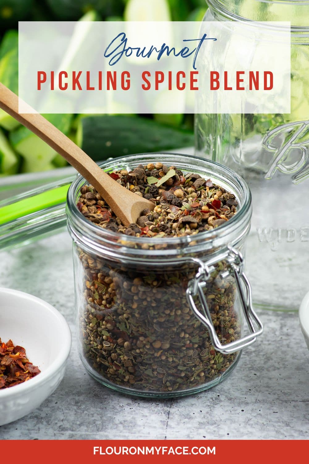 Small jar Gourmet Pickling Spice blend with cucumbers in background.