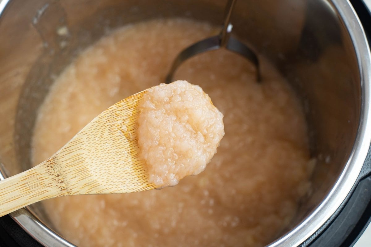 A wooden spoon with a spoonful of homemade applesauce.
