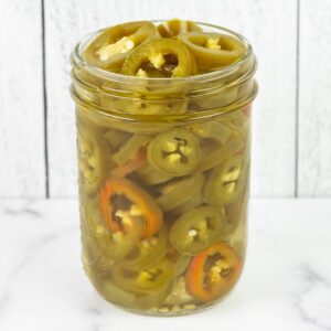 An over flowing jar of sliced pickled jalapenos.
