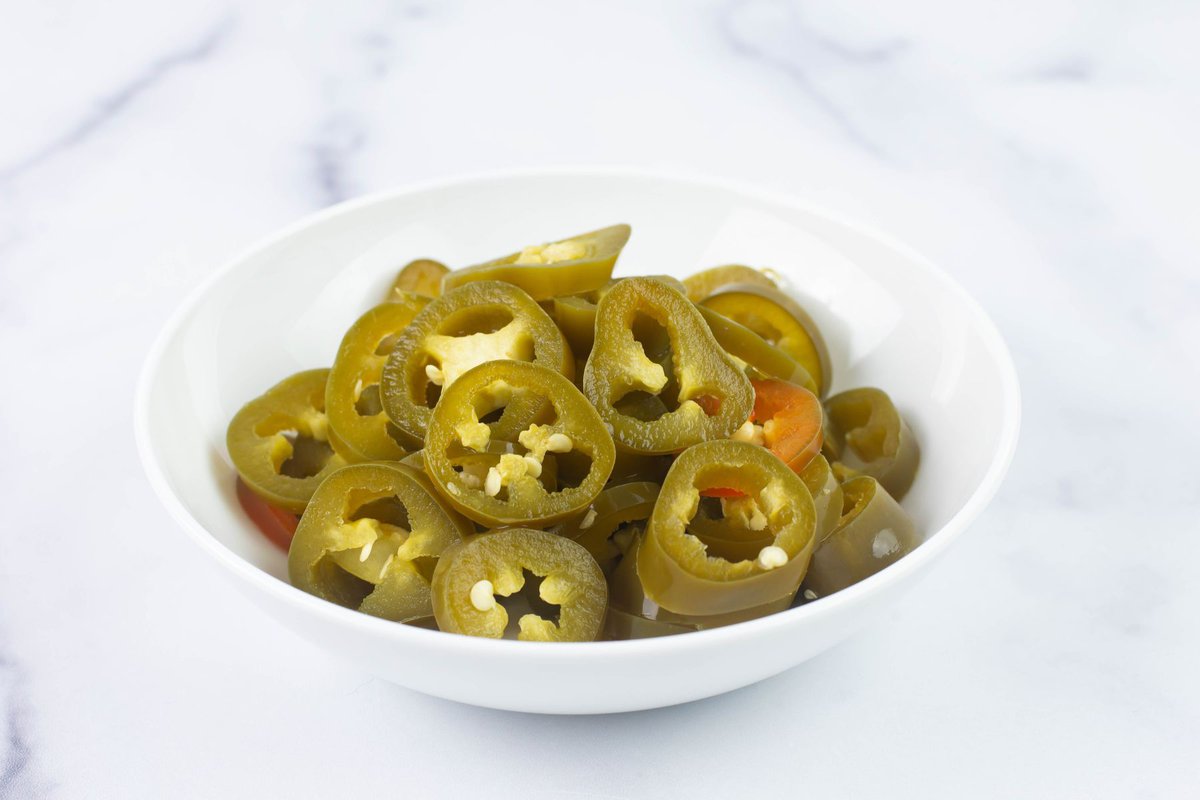 Sliced pickled peppers served in a small white bowl.