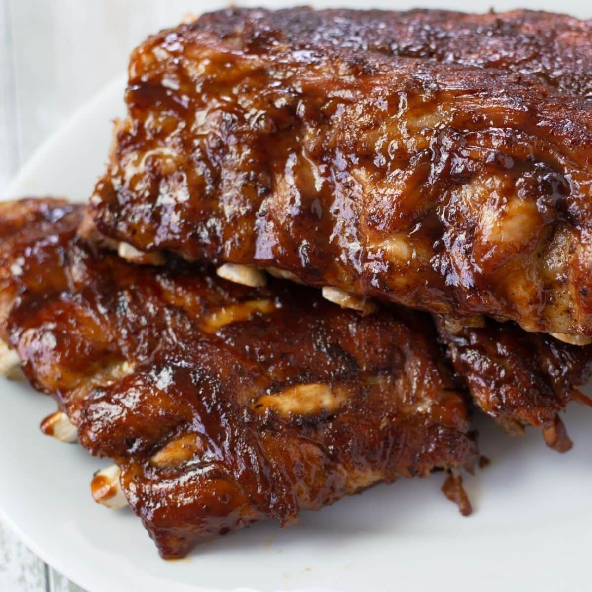 Two stacked racks of bbq ribs on a serving platter.