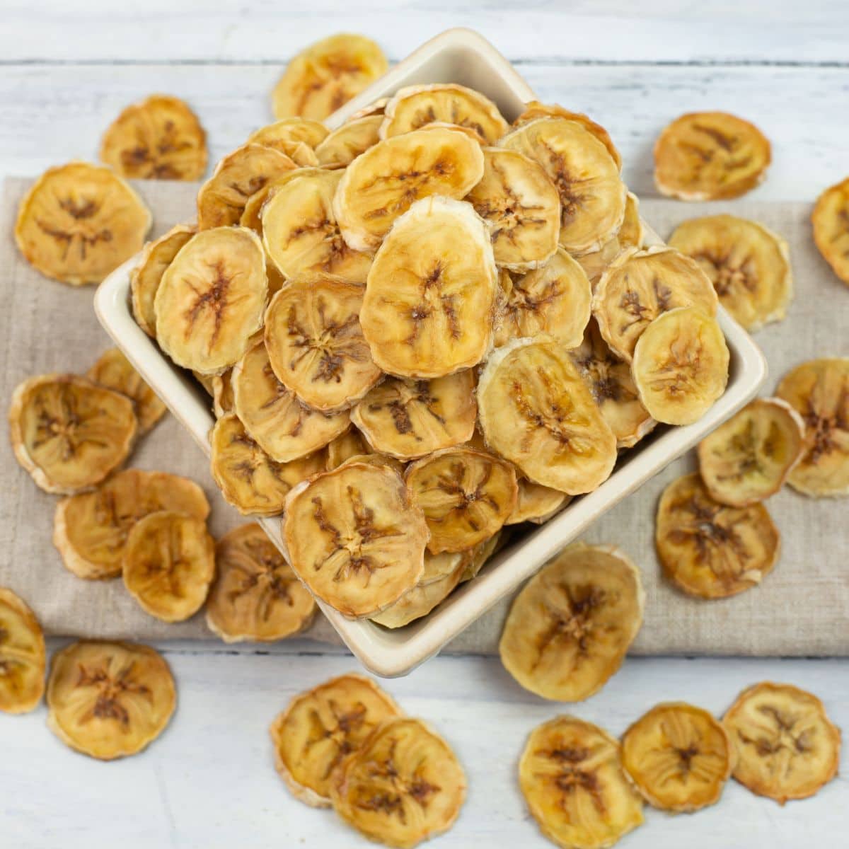 Dried banana chips in a square bowl.