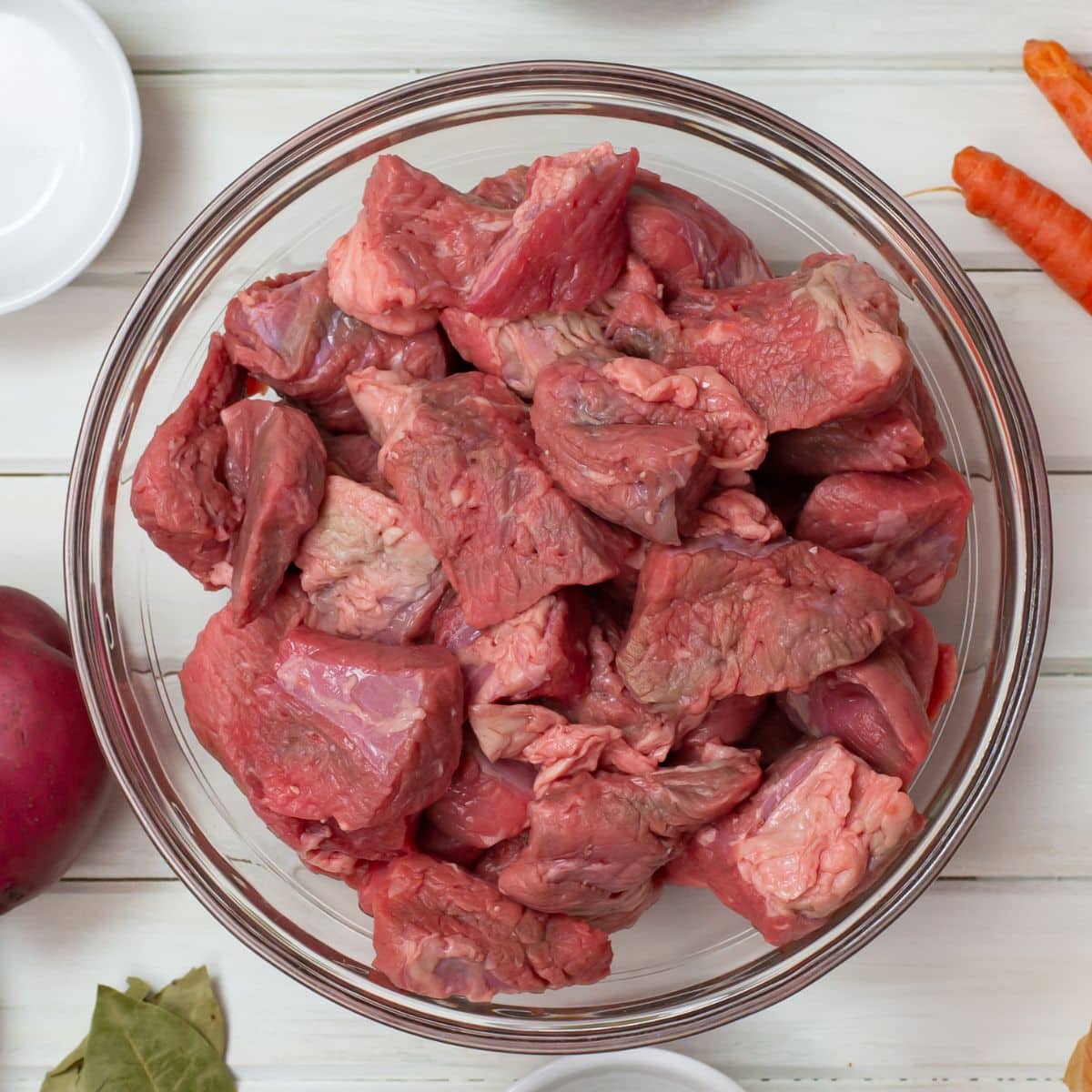 A glass bowl filled with chunks of beef for a crock pot beef recipe.