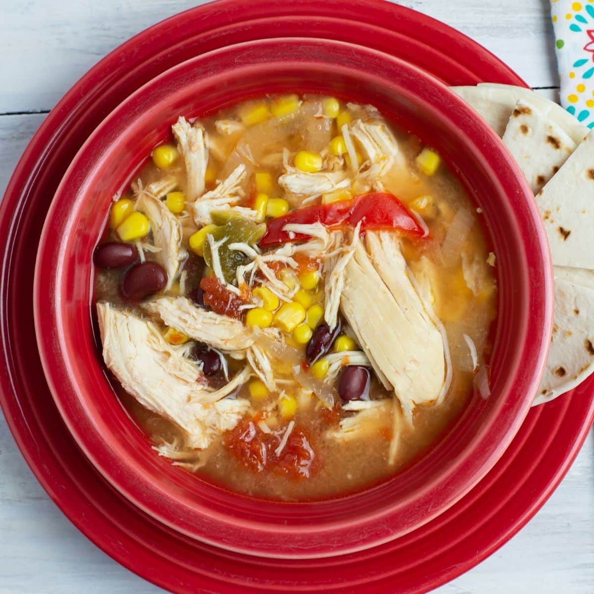 A red bowl filled with crock pot chicken soup recipes.