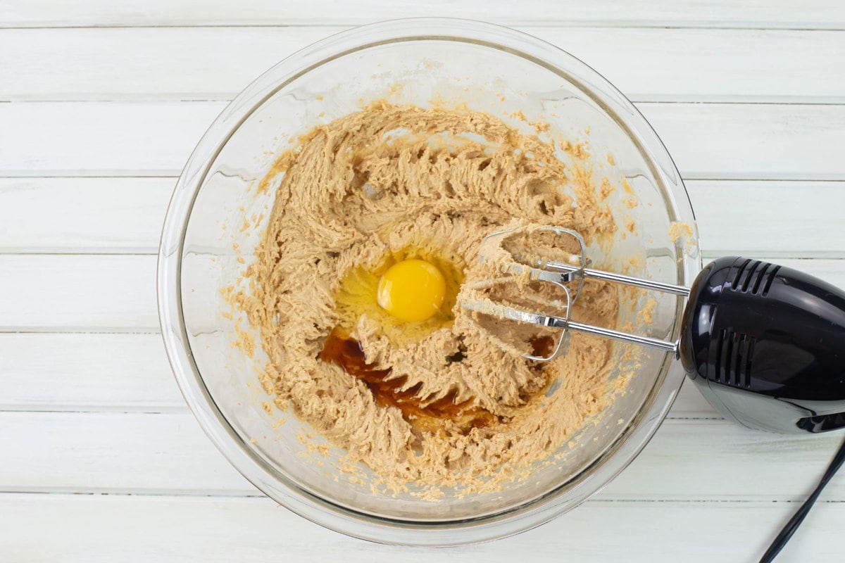 Adding egg and vanilla to the bowl of peanut butter mixture.