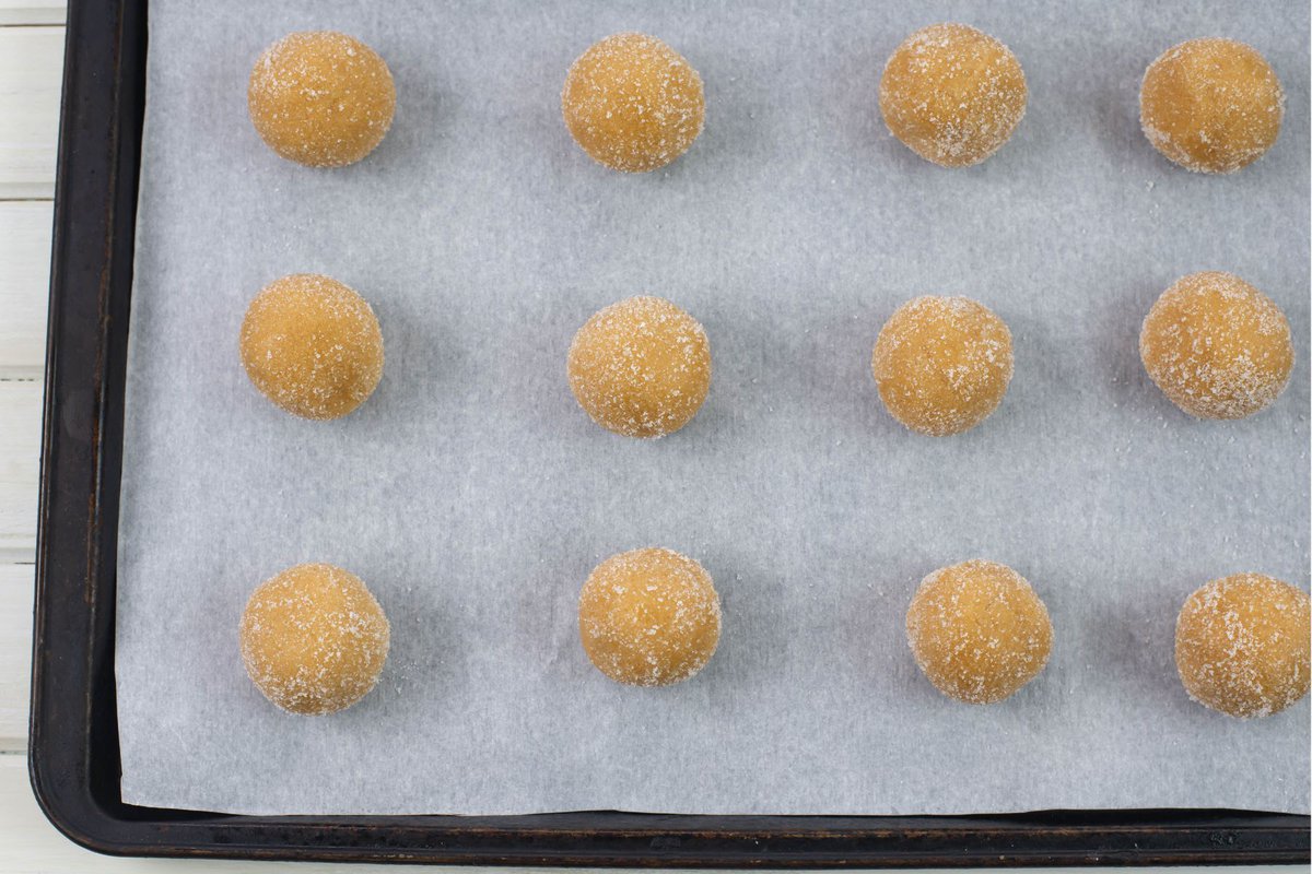 Peanut Butter cookie dough balls arranged on a cookie sheet.