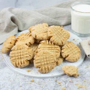 Peanut Butter Cookies on a white wooden tray with a glass of milk in the background.