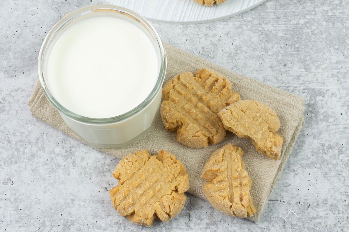 Peanut Butter cookies with a glass of milk on a cloth napkin.