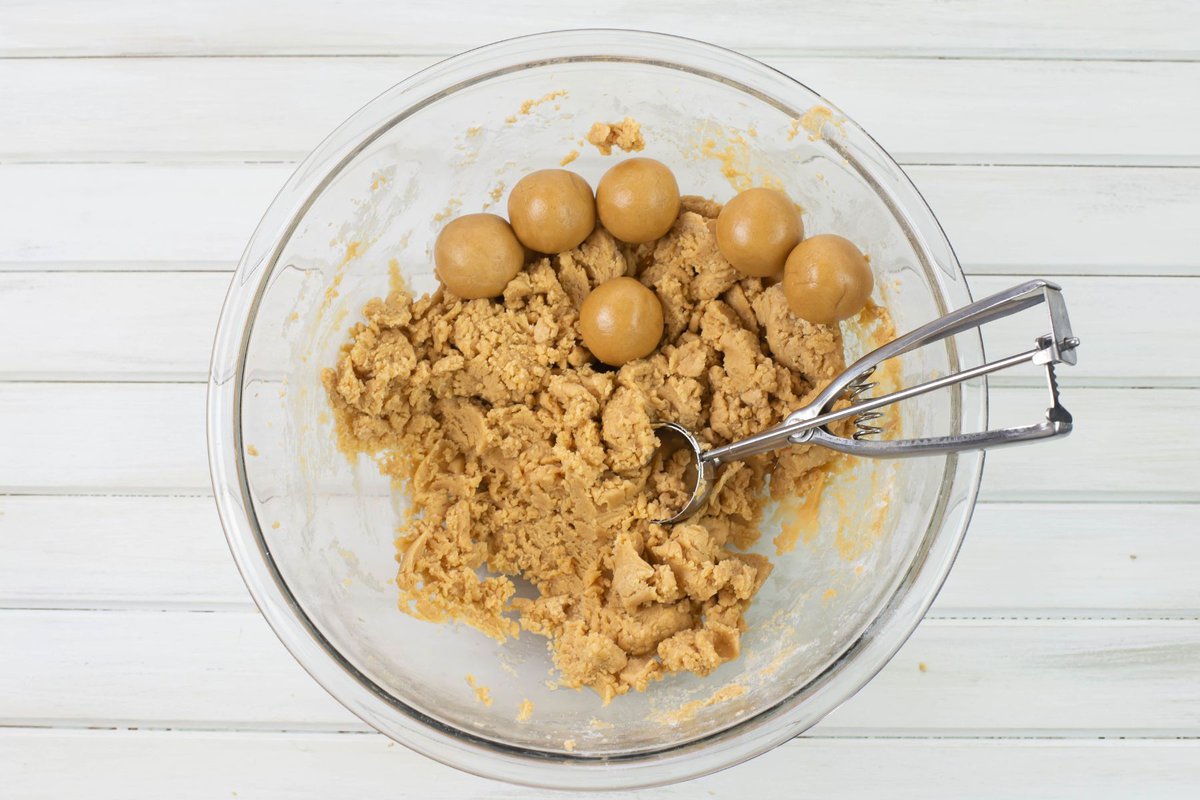 Shaping peanut butter cookie dough into balls using a dough scoop.
