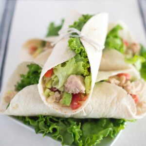 A plate with a stacked pile of Tuna wraps.