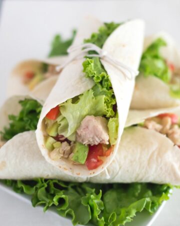 A plate with a stacked pile of Tuna wraps.