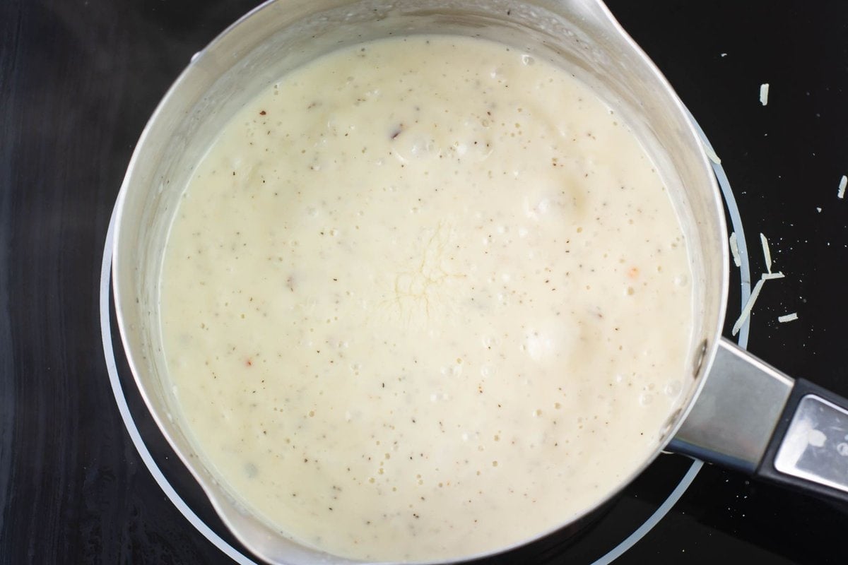 Overhead image of a small pot filled dwith homemade alfredo sauce.