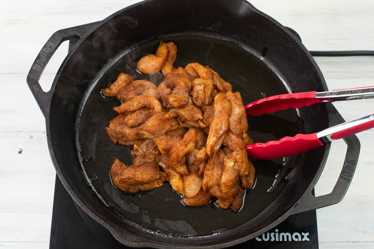 Adding chicken pieces to a hot cast iron skillet.