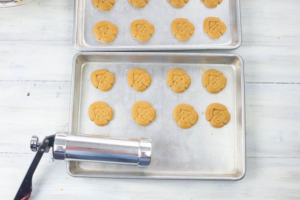 Pressing gingerbread Spritz cookies out onto the baking pan.