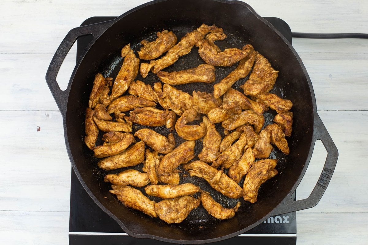 Seared chicken strips in a large skillet.