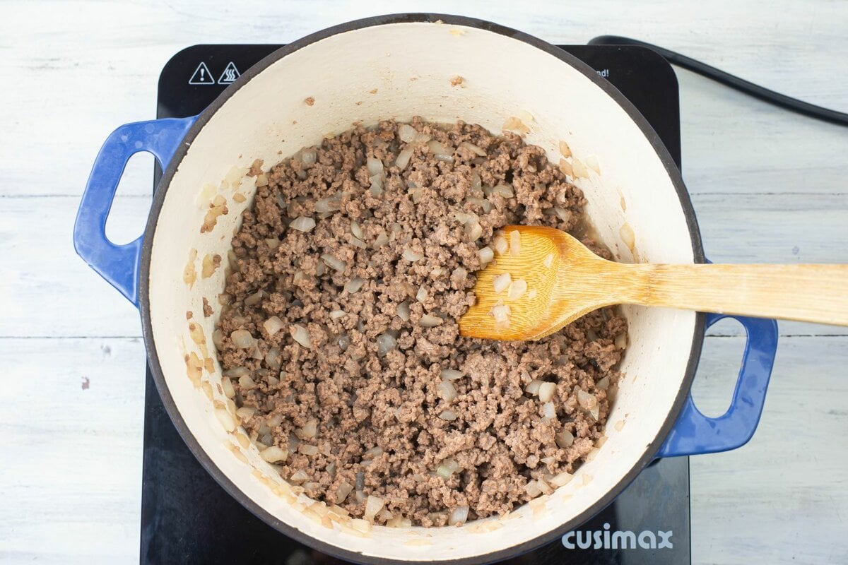 Browned ground beef with onions drained in a Dutch oven.