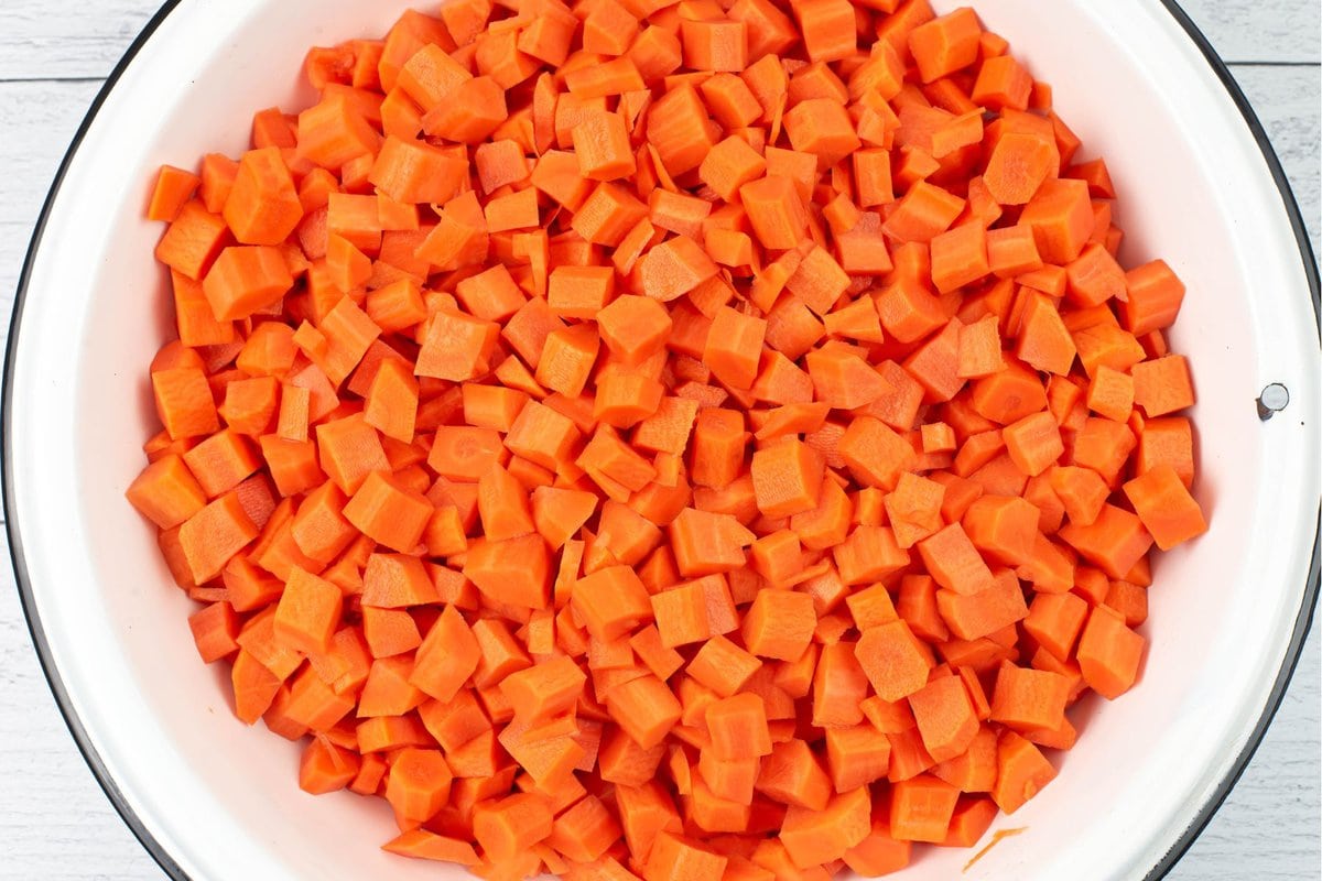Cubed blanched carrots in a large white enamel bowl.