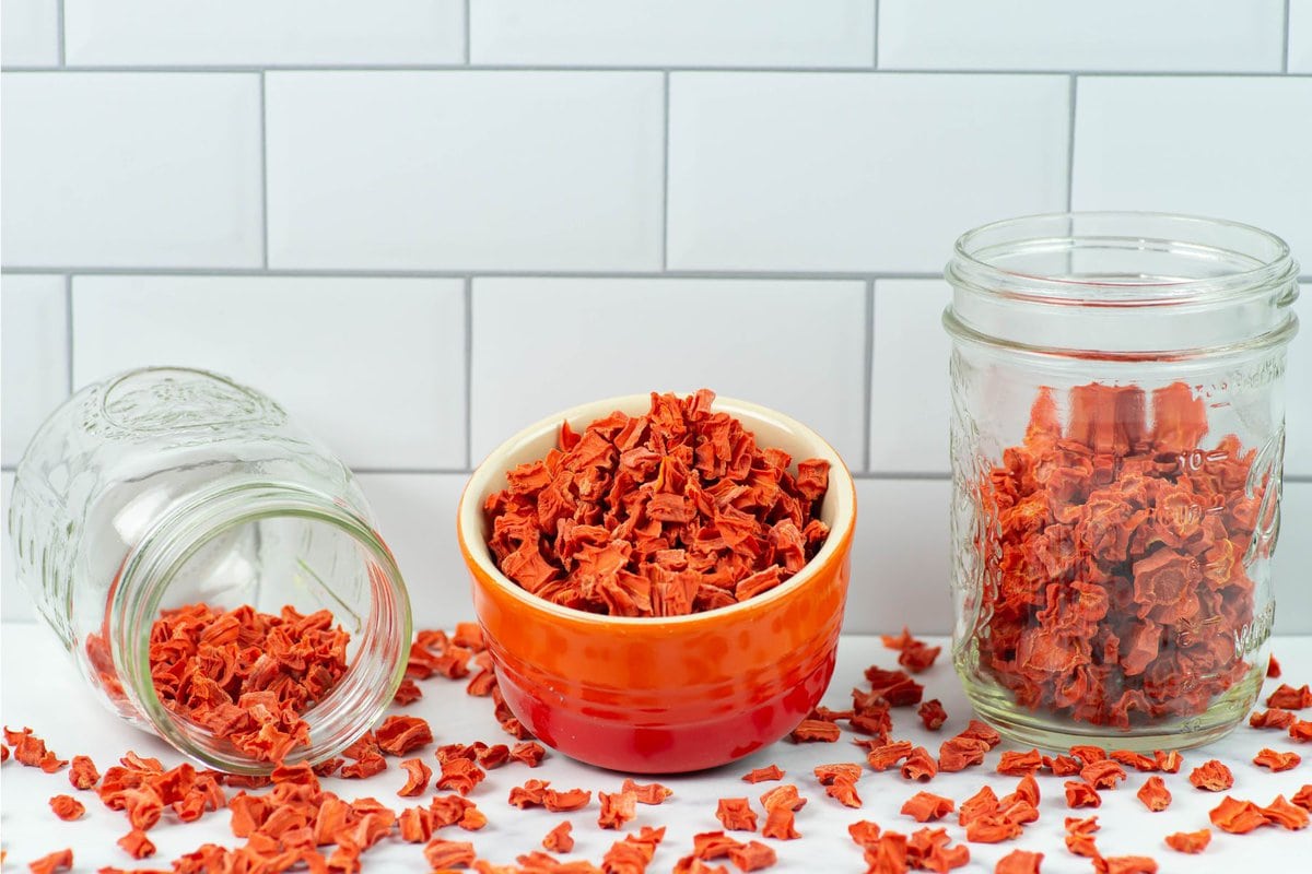 Cubed dehydrated carrots in a bowl and jars for storage.