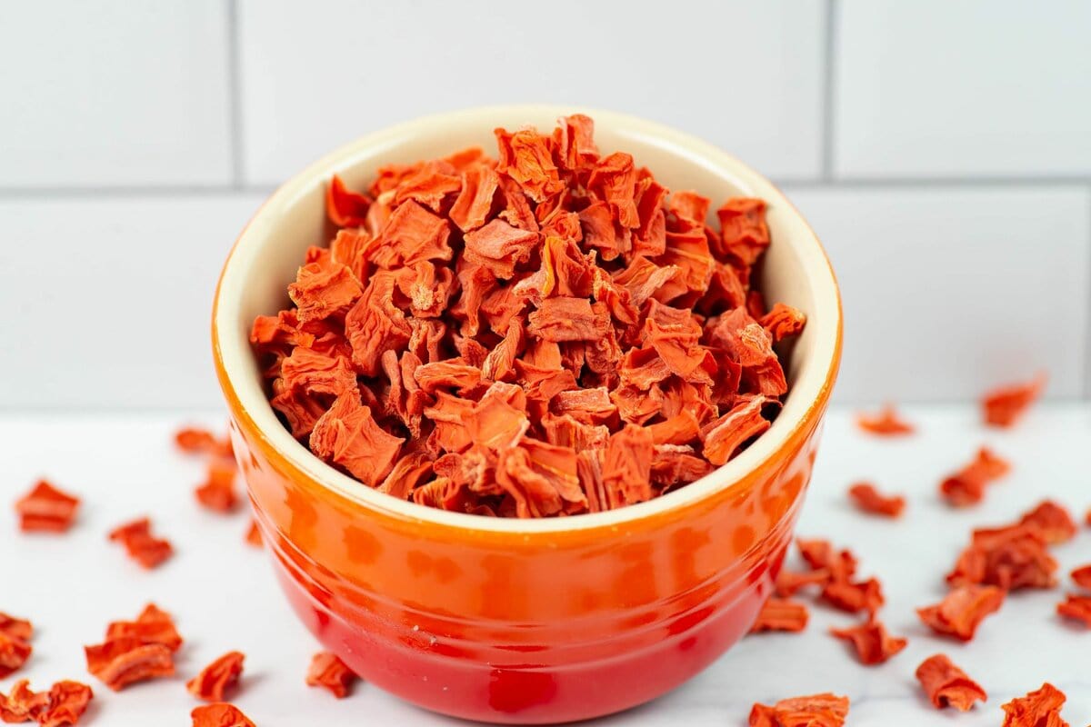 Dehydrated cubed carrots in a small glass bowl.