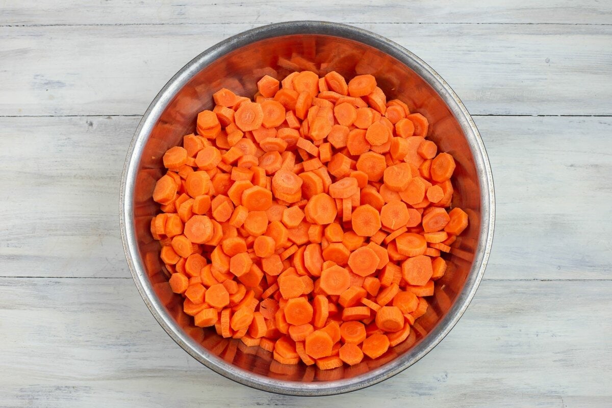A large aluminum bowl filled with sliced carrots.