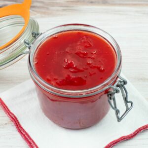 Homemade strawberry sauce in a glass canning jar with a bail type lid.