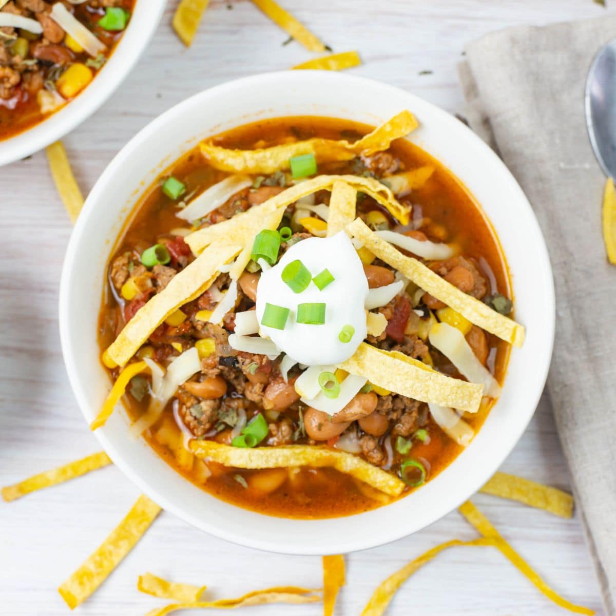 Overhead image of a bowl of Taco soup with toppings.