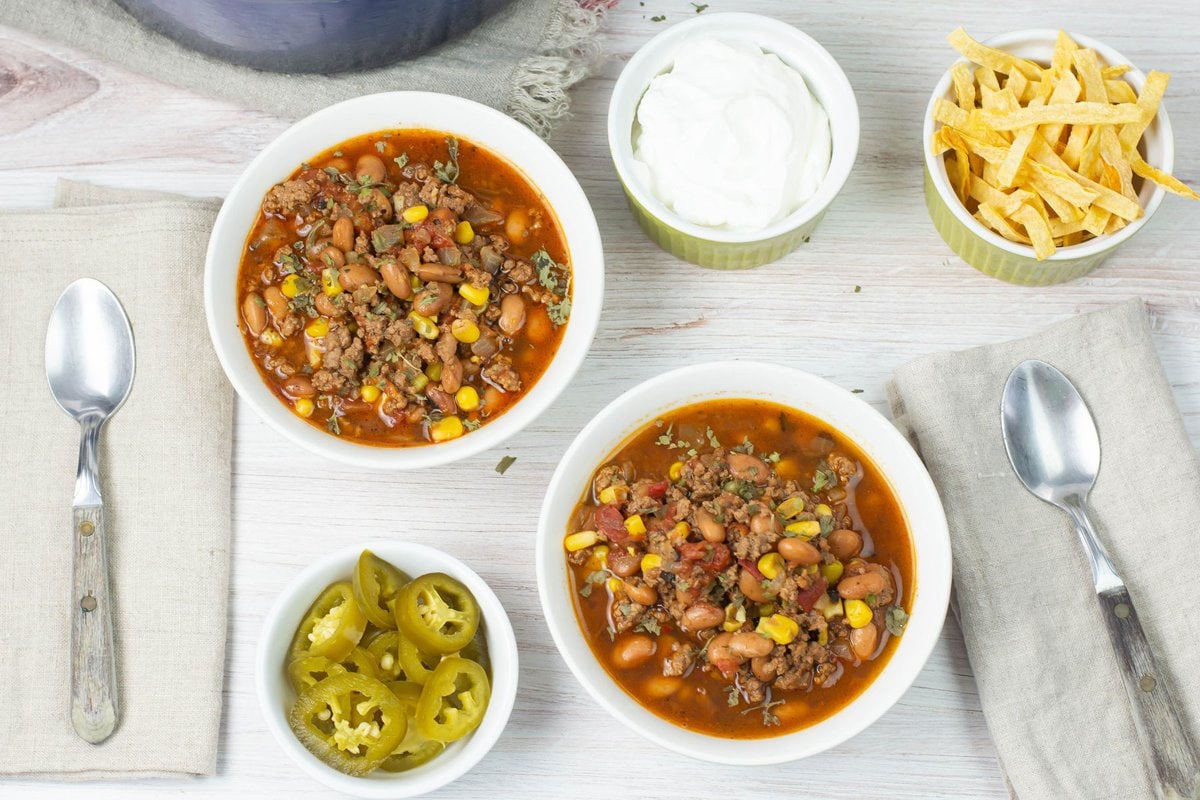 Two servings of taco soup with small bowl of toppings.