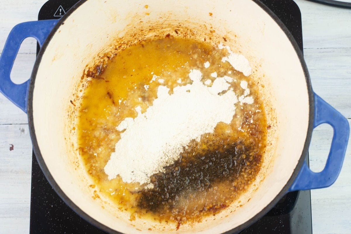 Adding flour, salt and pepper to the pan to make a roux.