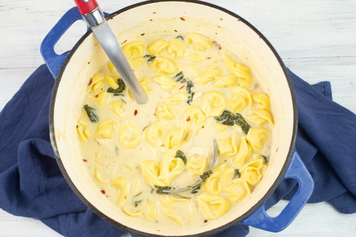 A Dutch oven pot filled with creamy chicken tortellini soup.