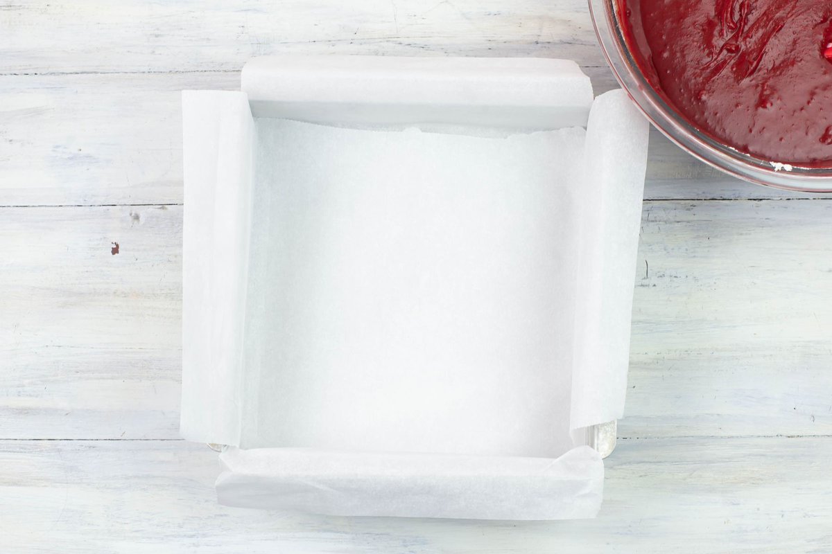 A square baking pan lined with parchment paper.