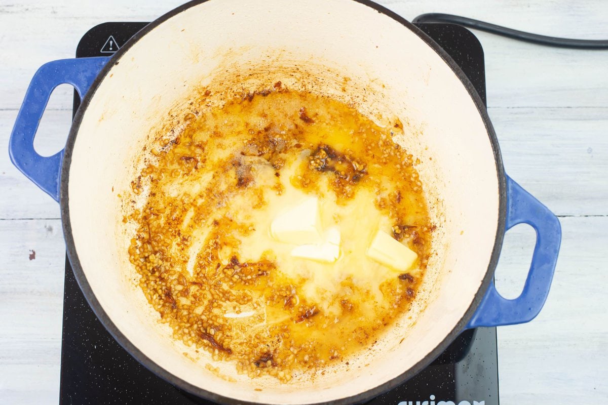 Melting the butter in the pan with minced garlic and pan drippings.