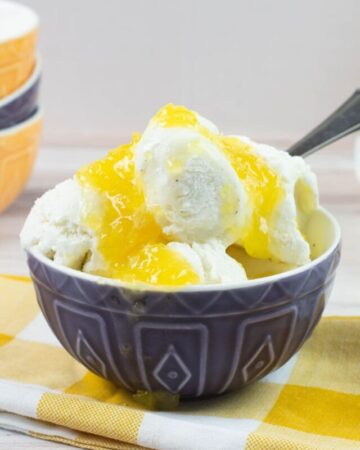 Vanilla ice cream with pineapple sauce in a blue bowl.