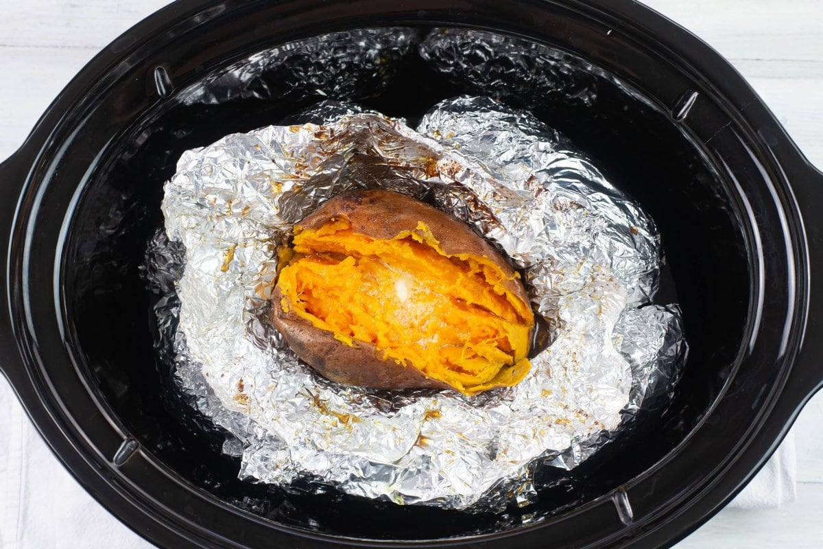 A baked crock Pot sweet potato split down the middle with a pat of melting butter.