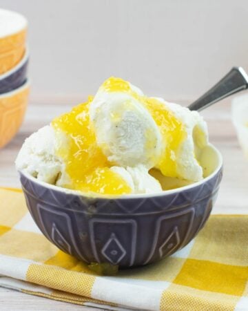 Vanilla ice cream with pineapple sauce in a blue bowl.