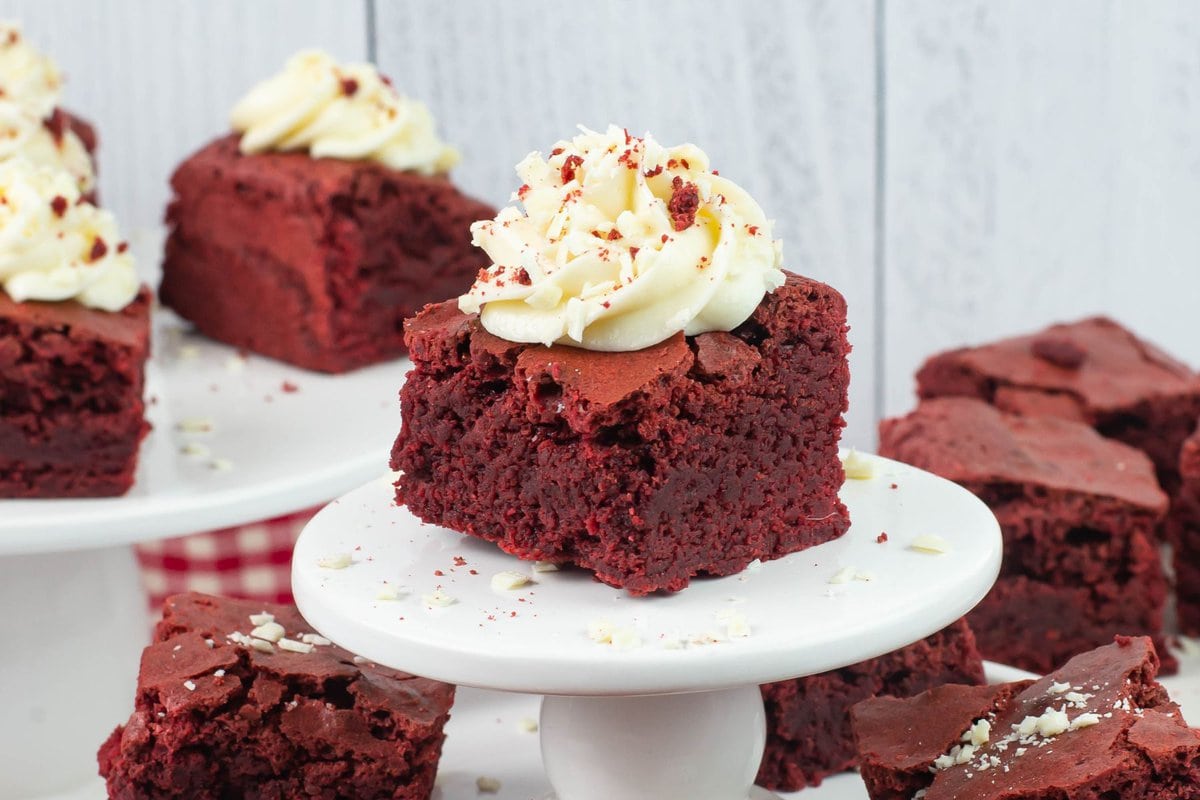 Frosted Red Velvet Brownies displayed on cake stands.
