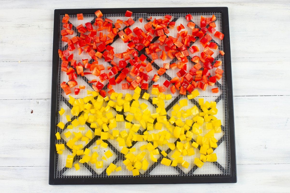 Diced red and yellow bell peppers on a drying tray.