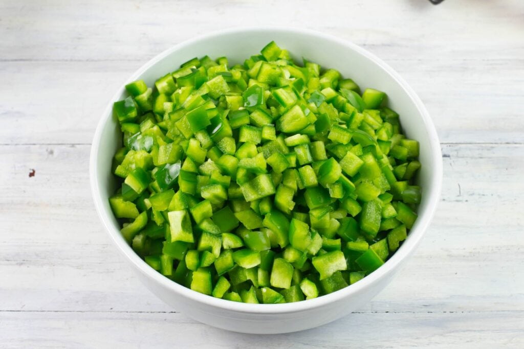 ½ inch cubes of diced green sweet bell pepper in a glass bowl.