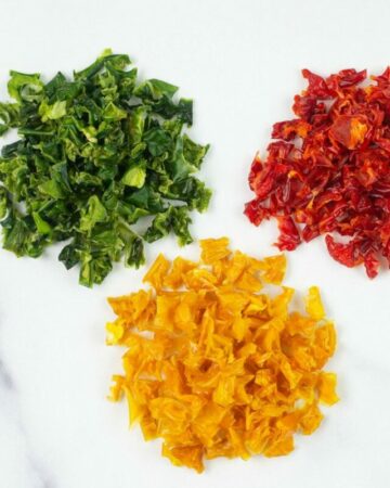 Small mounds of three different colored dried peppers.