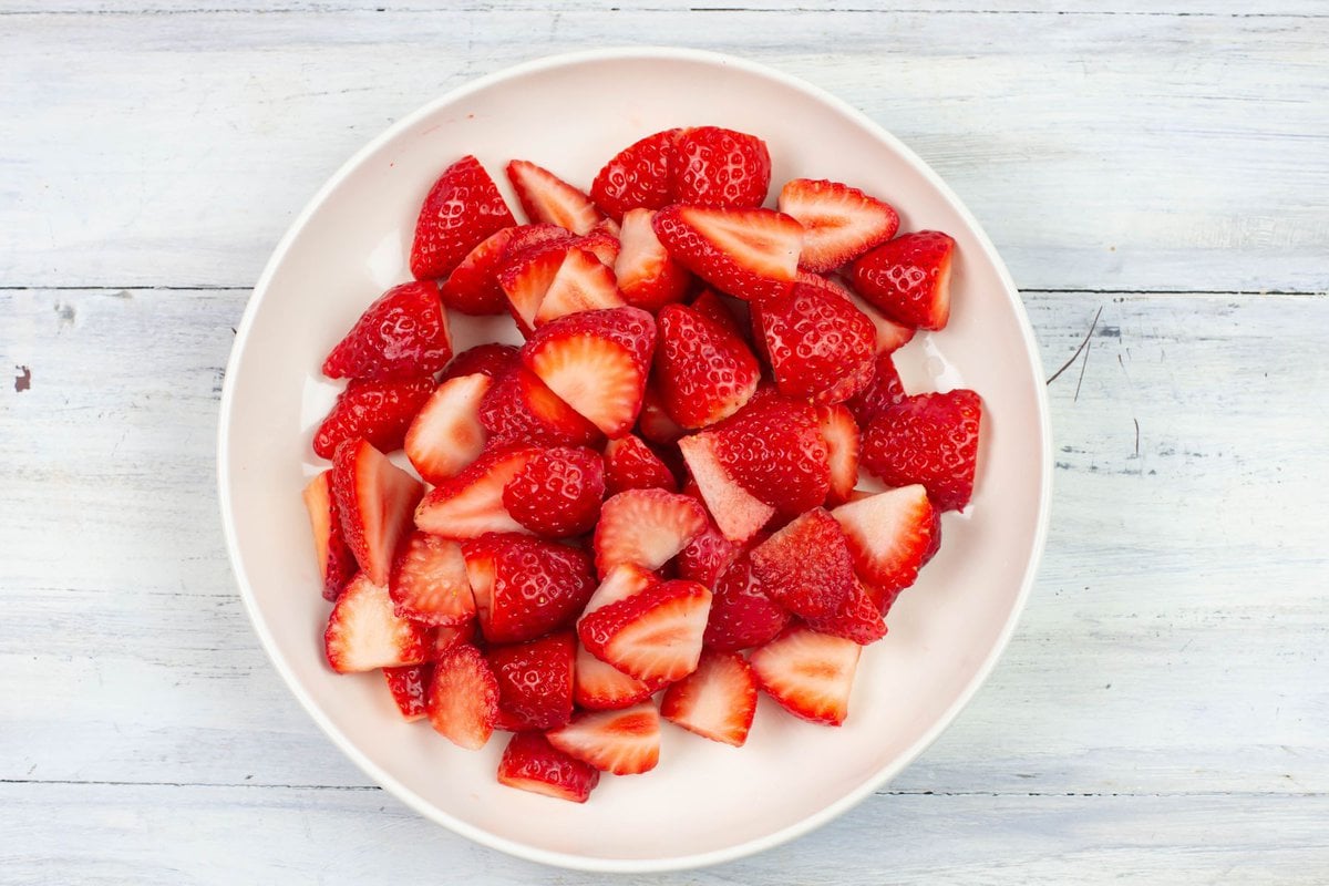 Sliced fresh strawberries in a white bowl.