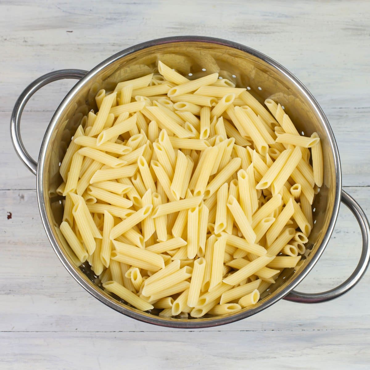 Cooked Penne Rigate pasta in a metal colander.