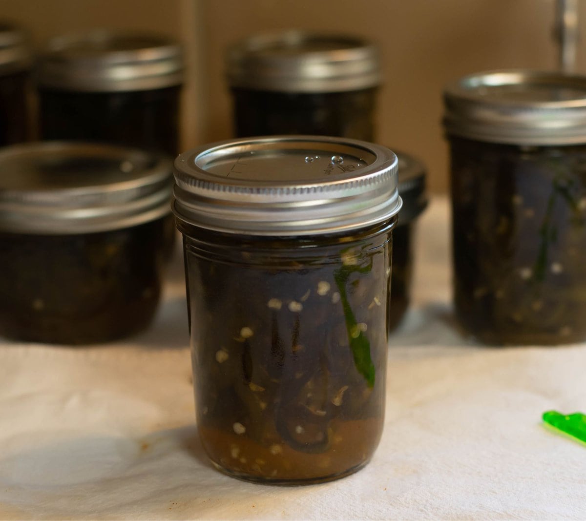 Hot water bath canned ½ pint jars of candied jalapenos cooling on a towel.