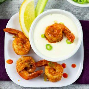 Plump Buffalo Shrimp served on an appetizer plate with a bowl of Garlic Parmesan Dressing.