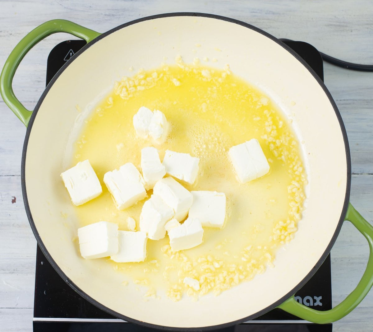 Melting cream cheese with butter and garlic in a skillet.