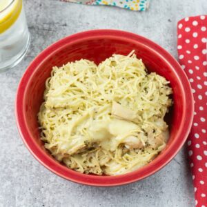 Creamy Pesto Chicken served with pasta in a red bowl.