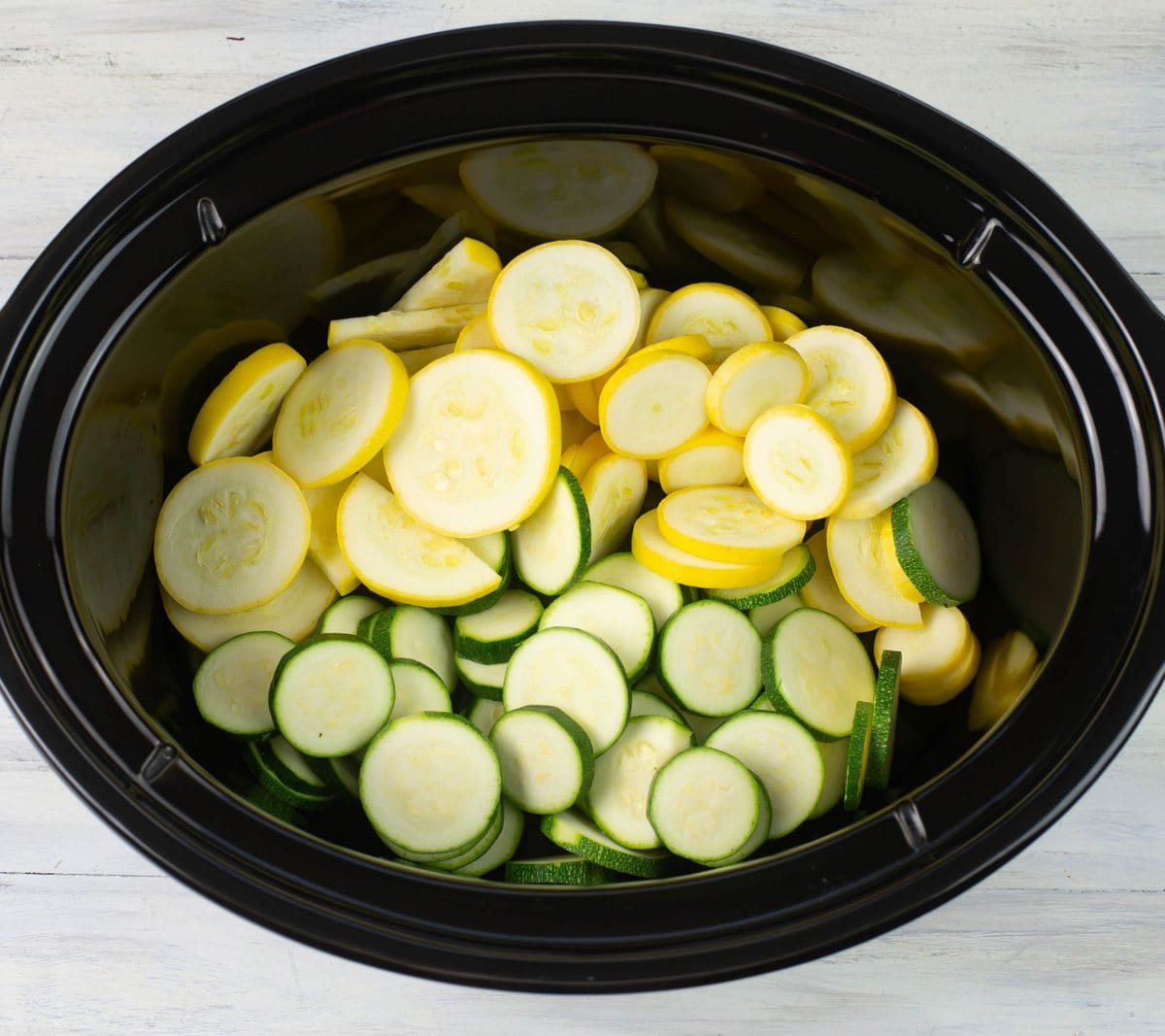 Sliced yellow squash and green zucchini in the crock pot. 