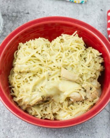 Creamy Pesto Chicken served with pasta in a red bowl.